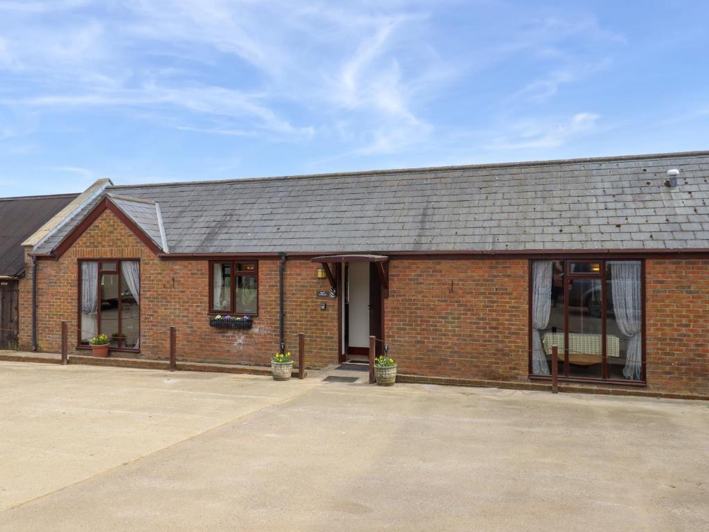 ein Backsteingebäude mit einer Tür und Fenstern in der Unterkunft Daisy Cottage in Bridport