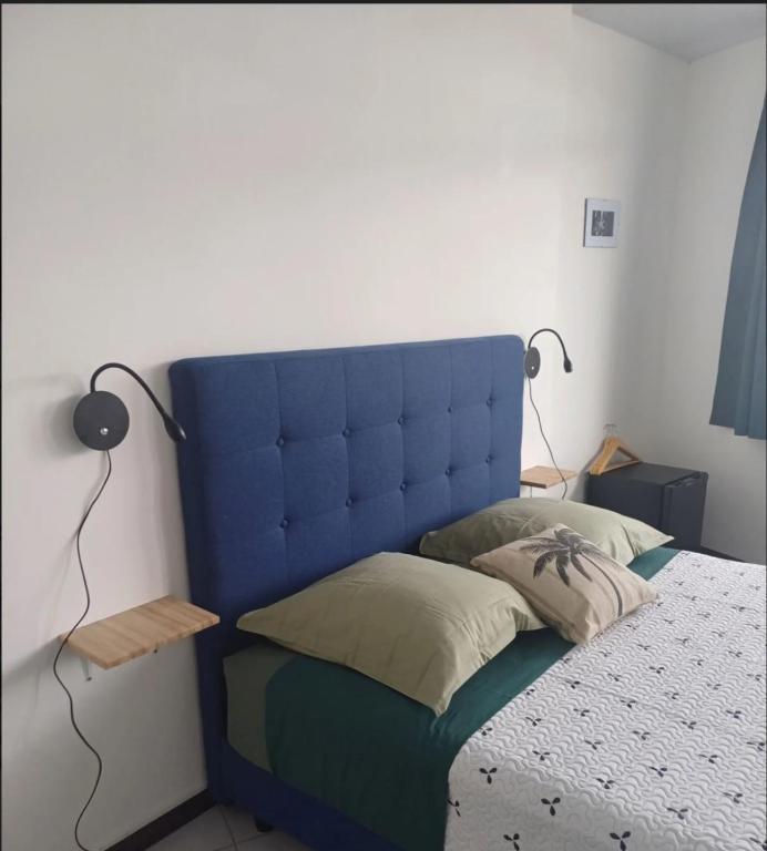 a bed with a blue headboard in a bedroom at Honey room city center in Papeete