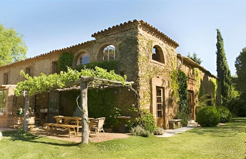 a stone building with a picnic table and an umbrella at Cortijo Rural Finca HUERTA SANTA MARÍA in Galaroza