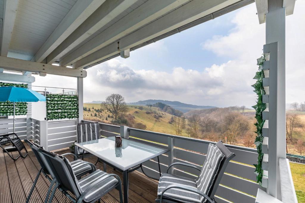a balcony with a table and chairs and a view at Ferienwohnung mit Aussicht in Notscheid