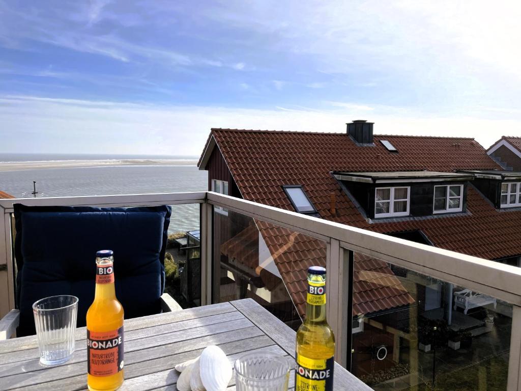 two bottles of beer sitting on a table on a balcony at Huus Waterkant 07 auf Amrum in Wittdün