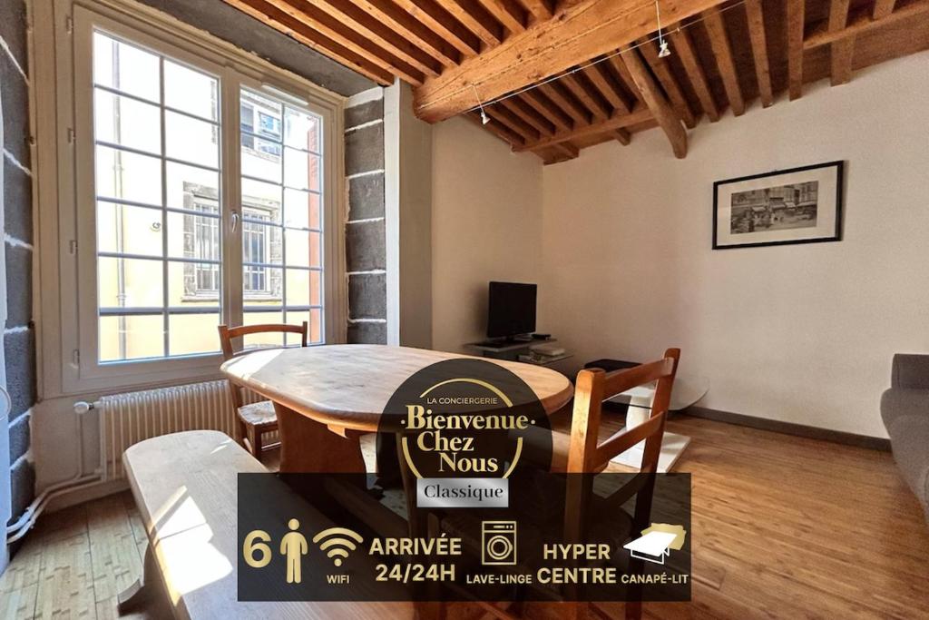 un salon avec une table et une grande fenêtre dans l'établissement Hypercentre maison de ville, rue piétonne animée, à Clermont-Ferrand