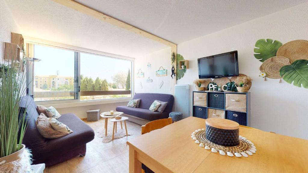 un salon avec un canapé et une table dans l'établissement Studio Cabine avec Piscine et Place de parking privée CAP D'AGDE, au Cap d'Agde