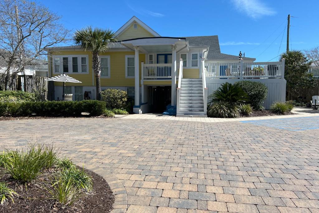 a yellow house with a porch and a driveway at Georgianne Suite Four in Tybee Island