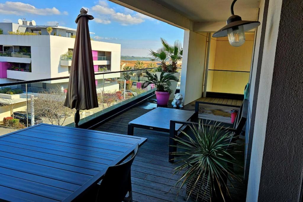 - un balcon avec une table bleue et un parasol dans l'établissement Beautiful T2 with pool - near beach, à Palavas-les-Flots