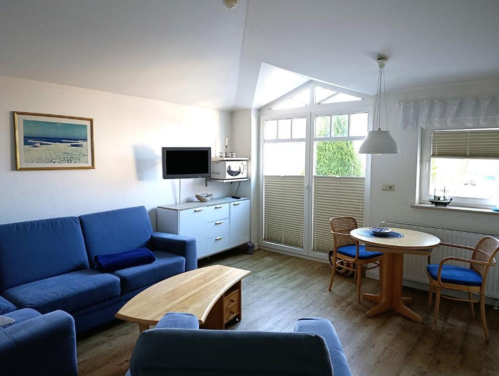 ein Wohnzimmer mit einem blauen Sofa und einem Tisch in der Unterkunft Fewo Rosenhof 16 in Kühlungsborn