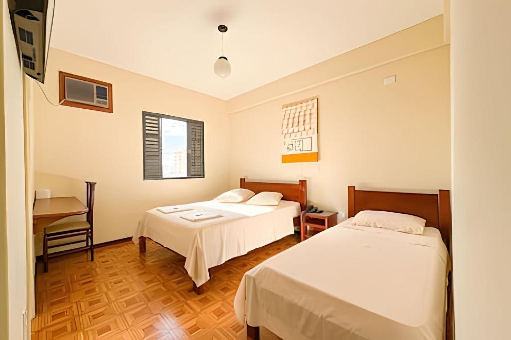 a hotel room with two beds and a desk at LN Flats & Suites in Uberlândia
