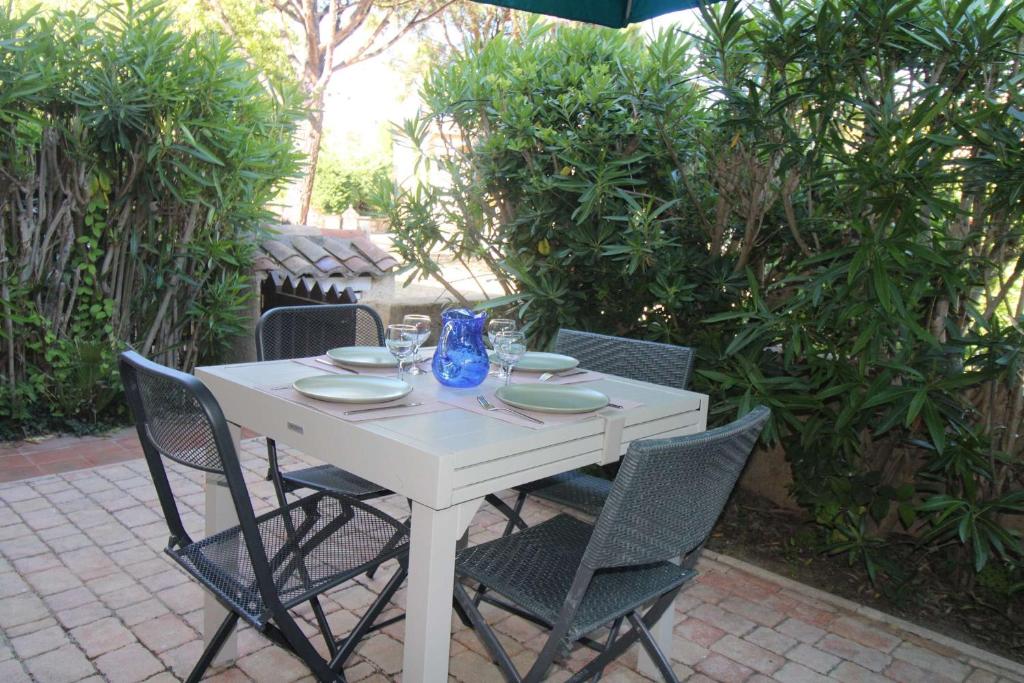 une table blanche avec des chaises et un vase bleu dessus dans l'établissement Gasjoly - Golfe de St-Tropez Studio avec cabine climatisé pour 4 personnes, à Gassin