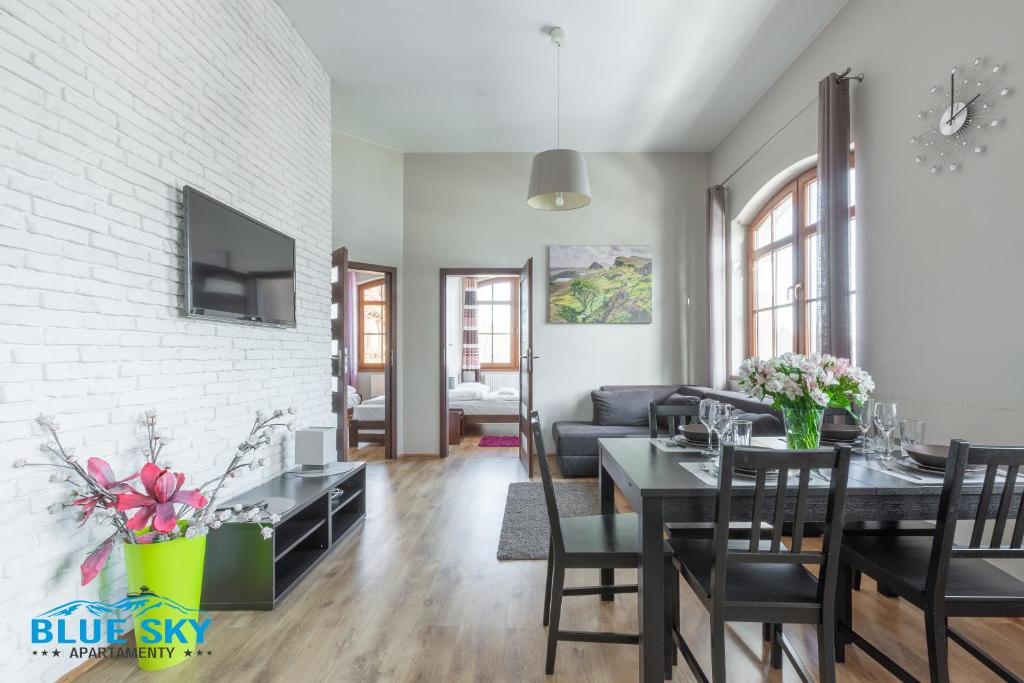 a dining room and living room with a table and chairs at Blue Sky - Apartamenty w centrum, blisko deptaka, restauracji i atrakcji Karpacza - Obrońców Pokoju 1D in Karpacz
