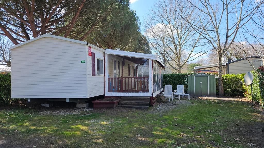 une petite maison blanche avec deux chaises dans une cour dans l'établissement Joli Mobil home N137, 4ch tout confort et spacieux, à Gastes