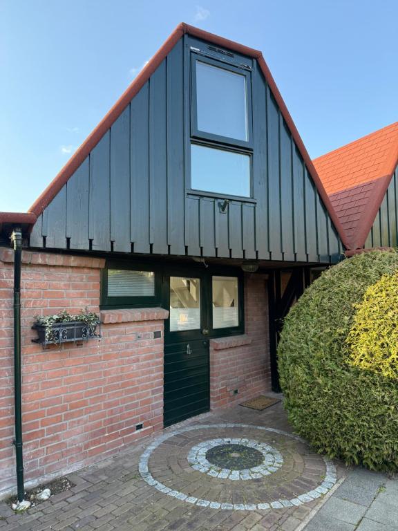 a house with a black roof and a brick wall at Stillwater Lodge De Rijd in Nieuwe-Niedorp