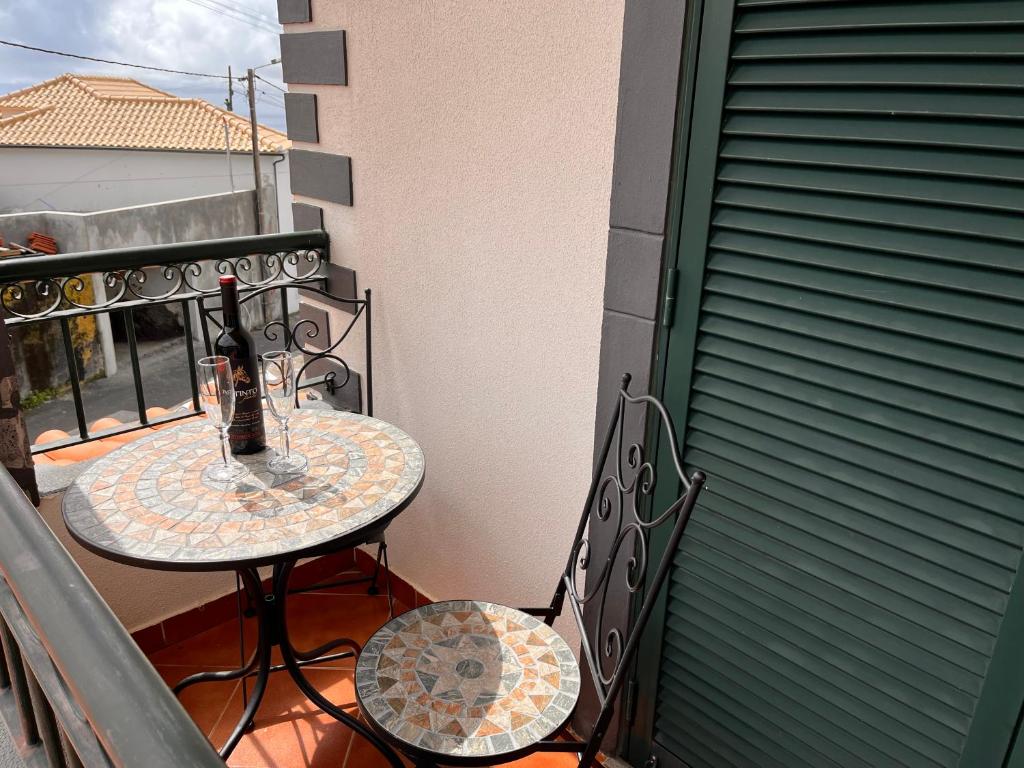 a table and chairs on a balcony with a bottle of wine at Apartamento Pestana in Arco da Calheta
