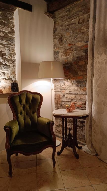 a green chair sitting next to a table with a lamp at Il Vicolo agli Orti - Centro storico - Lake Como in Bellano