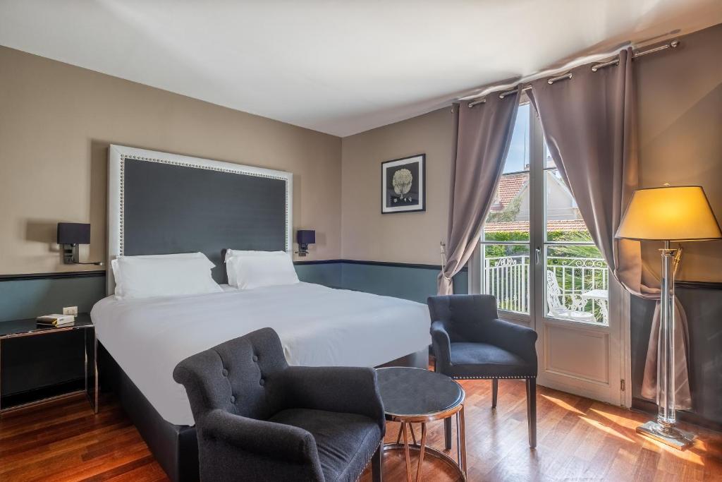 a hotel room with a bed and two chairs and a window at La Villa Mauresque in Saint-Raphaël