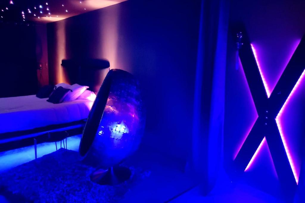 une chambre avec un lit et une télévision dans une pièce bleue dans l'établissement Suite Chic&Sensuelle La Manova SPA&Loveroom, à Saint-Martin-dʼAuxigny
