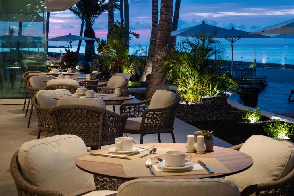 a restaurant with tables and chairs and a view of the ocean at Plus Fariones Suite Hotel in Puerto del Carmen