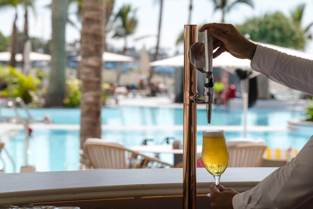 a person is pouring a glass of beer at a table at Plus Fariones Suite Hotel in Puerto del Carmen