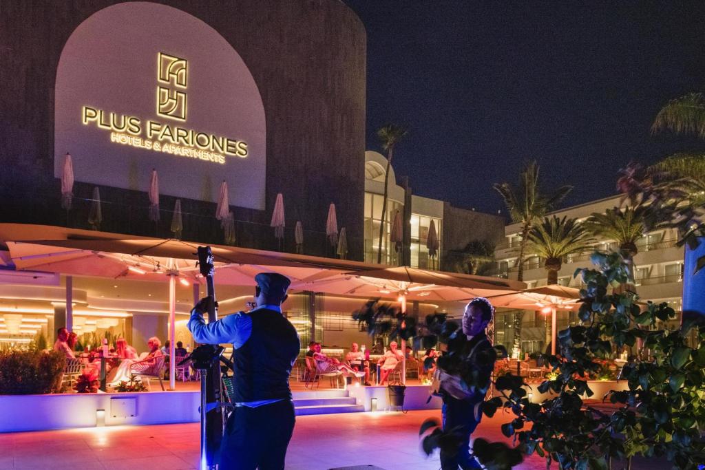 two people standing in front of a building at night at Plus Fariones Suite Hotel in Puerto del Carmen