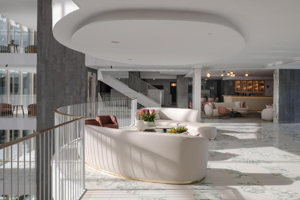 a lobby with white furniture and a staircase at Plus Fariones Suite Hotel in Puerto del Carmen