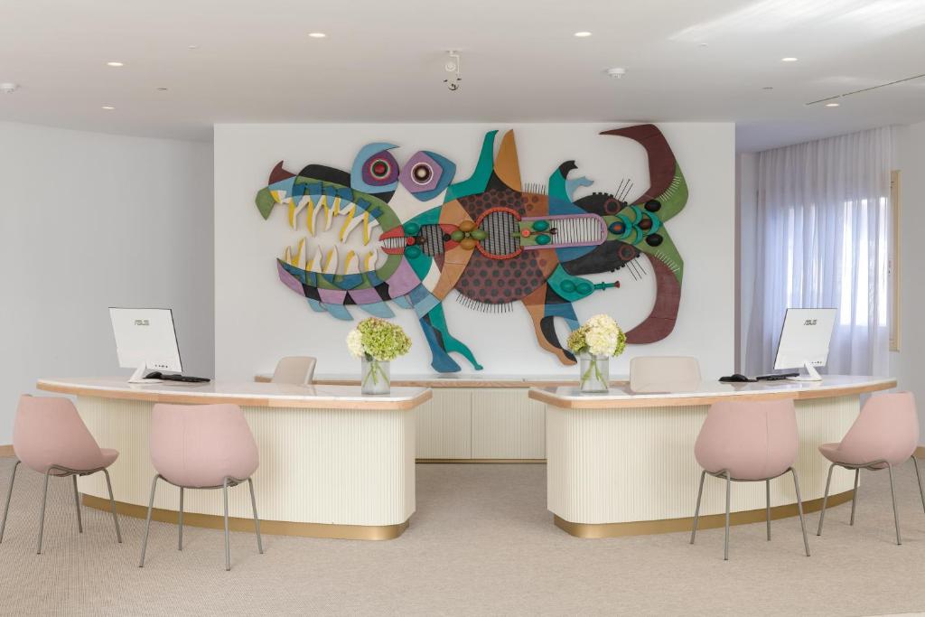 a lobby with two reception desks with pink chairs at Plus Fariones Suite Hotel in Puerto del Carmen