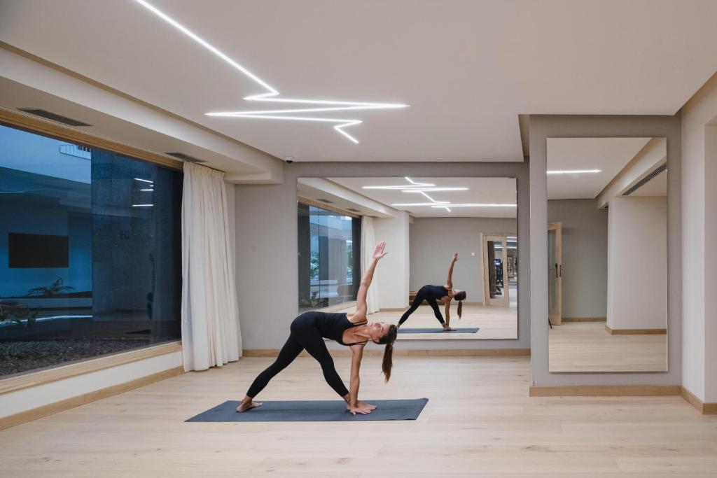 a woman doing a yoga pose in a room at Plus Fariones Suite Hotel in Puerto del Carmen