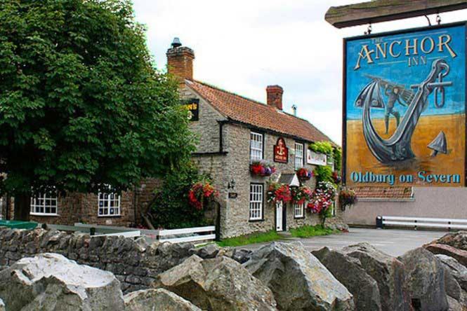 um edifício de pedra com um sinal na lateral em The Anchor Inn em Thornbury