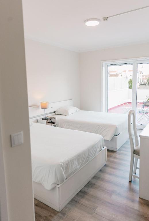duas camas num quarto com uma mesa e uma cadeira em Arca Nova Guest House - Caminha em Caminha