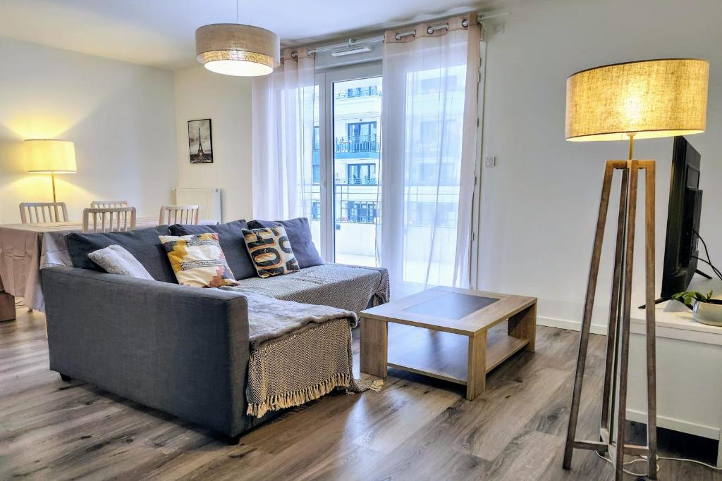 un salon avec un canapé et une table dans l'établissement Modern 2BR balcony secured parking metro 14, à Saint-Ouen