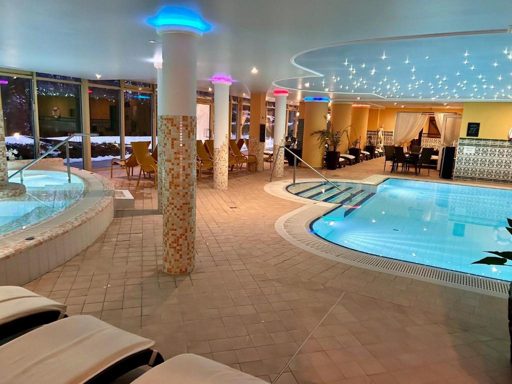 a large pool in a hotel with tables and chairs at Calimbra Wellness Hotel Superior in Miskolctapolca