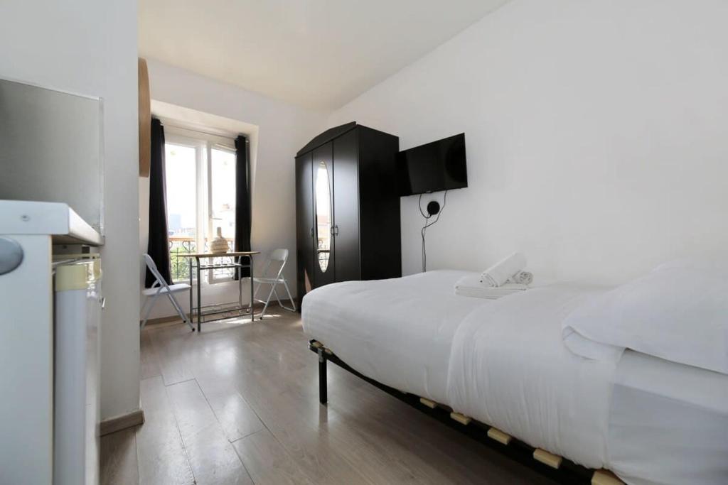 une chambre avec un grand lit blanc et une cuisine dans l'établissement Studio moderne hopital Cochin - Paris 13 - 2P, à Paris
