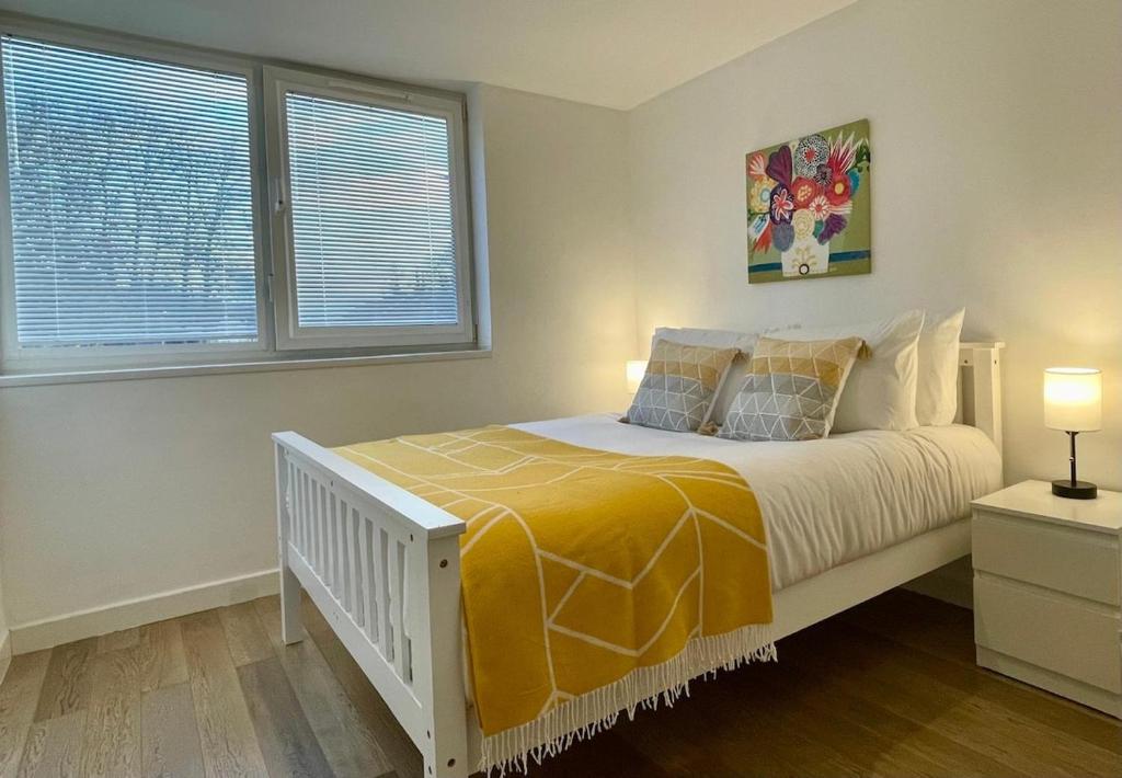 a bedroom with a white bed with a yellow blanket at Convenient quiet flat with parking in Andover