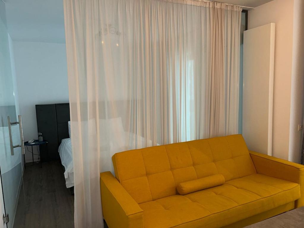 un sofá amarillo en una sala de estar con cortinas en Nor Apartament, en Bucarest