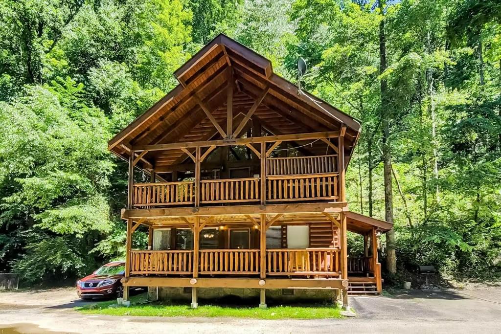 a large wooden cabin in the middle of a forest at Cozy Cabin Wgame Room, Hot Tub & Creek in Pigeon Forge