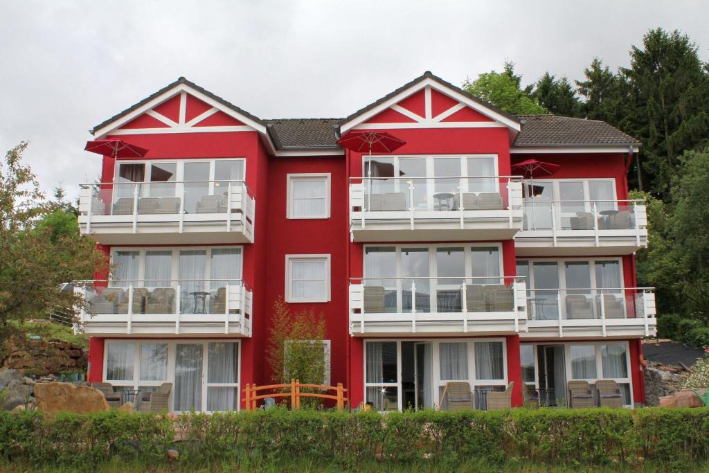 a red house with white balconies on the side of it at Appartement In Schalkenmehren Mit Schönem Balkon in Schalkenmehren