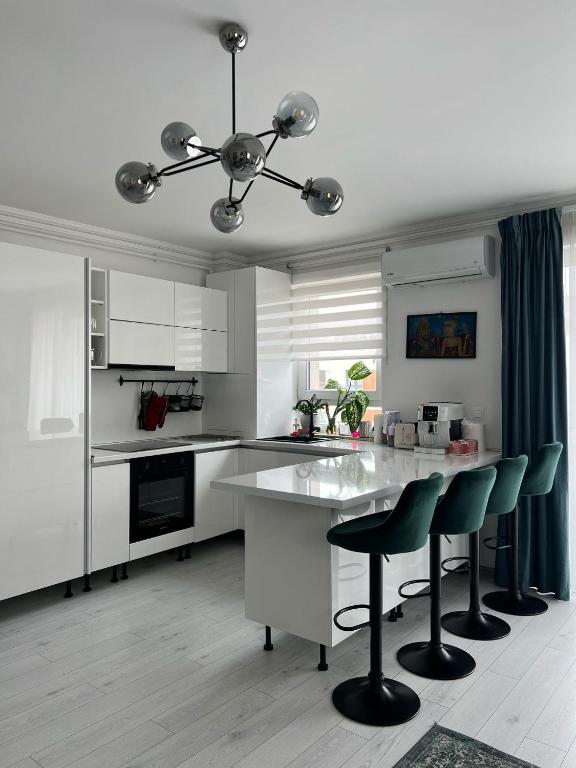 a kitchen with white cabinets and a table and chairs at 12 Apartament in Târgu-Mureş