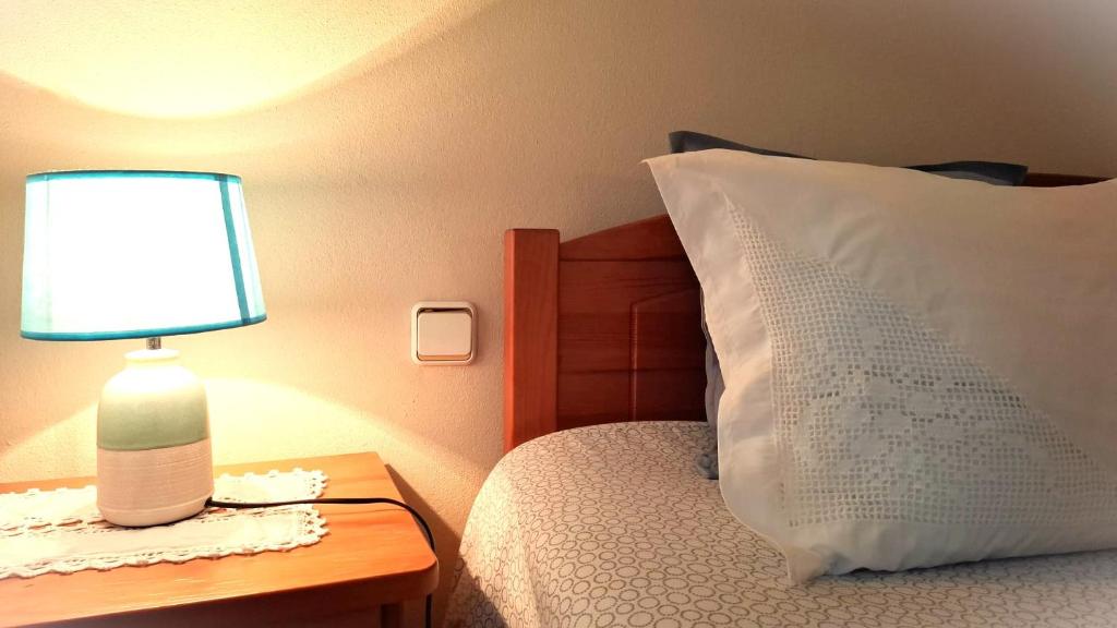 a bed with a lamp on a table next to a pillow at Aljezur Coast Apartment - Villa Luar in Aljezur