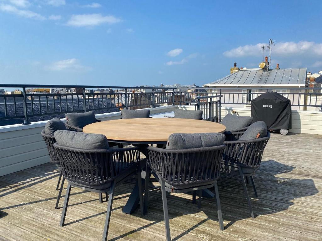 une table et des chaises en bois sur une terrasse avec une table dans l'établissement Les Hirondelles de Trouville, à Trouville-sur-Mer
