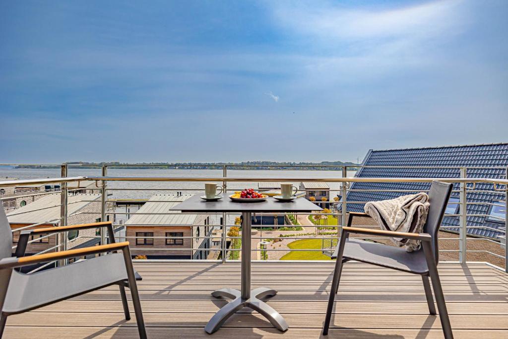 ein Tisch und Stühle auf einem Balkon mit Blick auf das Meer in der Unterkunft Deluxe Studio-Apartment "Wiking-Koje 11" direkt an der Schlei in Schleswig