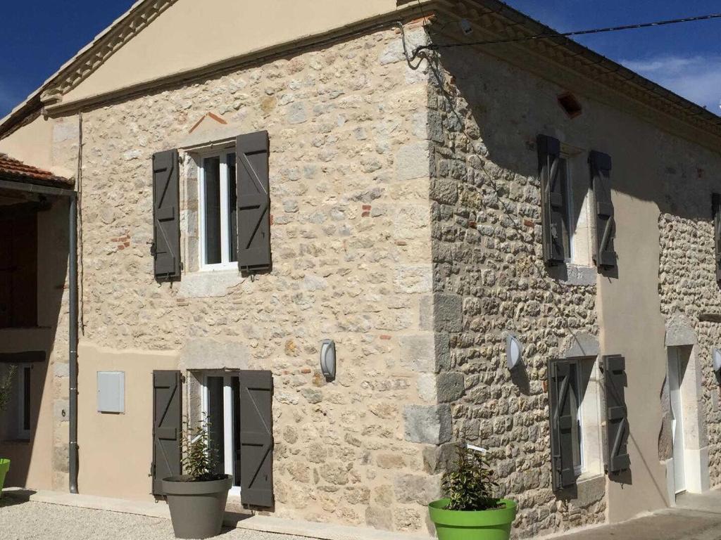 una casa in pietra con persiane nere su un edificio di Mas del sol a Cahuzac-sur-Vère