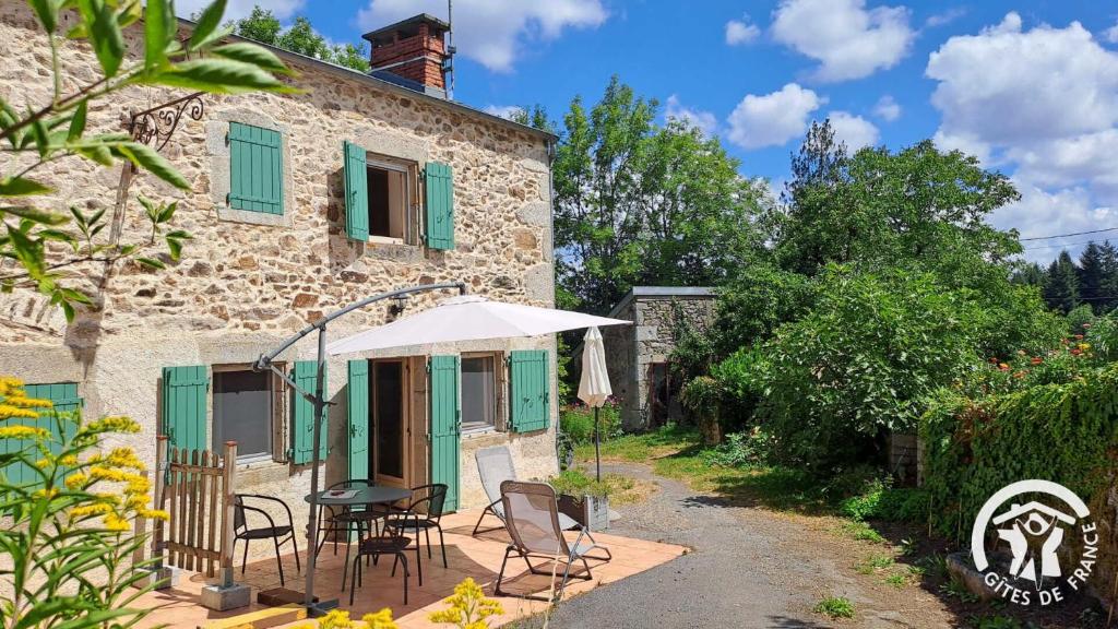 una casa con mesa, sillas y sombrilla en Guyor, en Le Bez