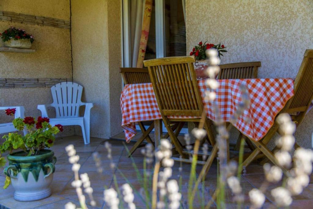 d'une terrasse avec des chaises et une table avec un tissu de table rouge et blanc. dans l'établissement L'hermitage, à Ambres