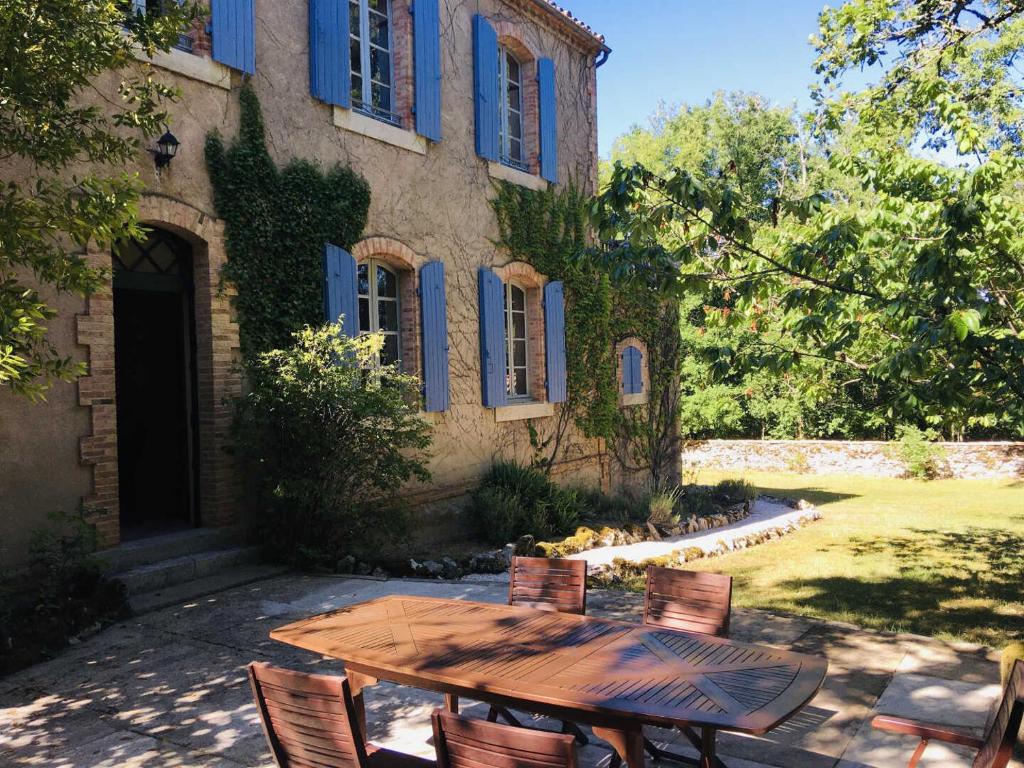 a wooden table and chairs in front of a building at Ancienne ecole de moncere in Penne