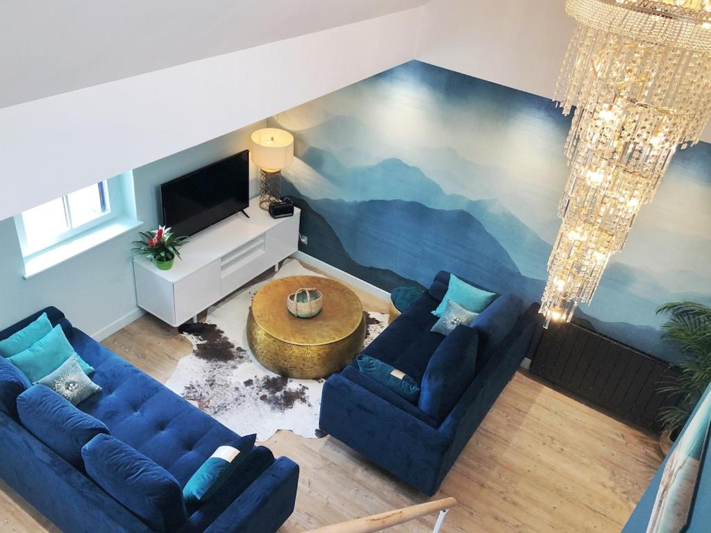 un salon avec des canapés bleus et une fresque murale. dans l'établissement Amazing sea view modern apartment Port de la Houle, à Cancale