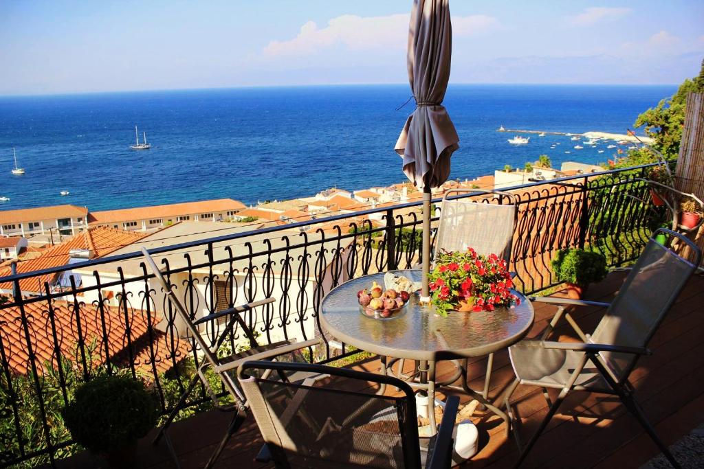 un balcón con una mesa y una sombrilla y el océano en Violetta Rooms, en Koroni