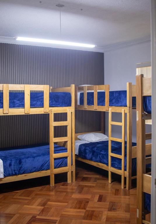 a room with three bunk beds with blue sheets at Gutierrez Hostel in Lima