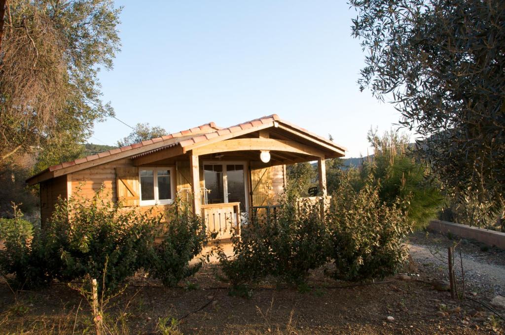 a small wooden house with a porch in a field at Les chalets du Relais d'Aguilar in Tuchan