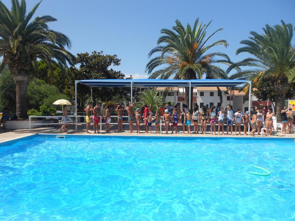 a group of people sitting on chairs next to a pool at Residence La Giungla in Falerna