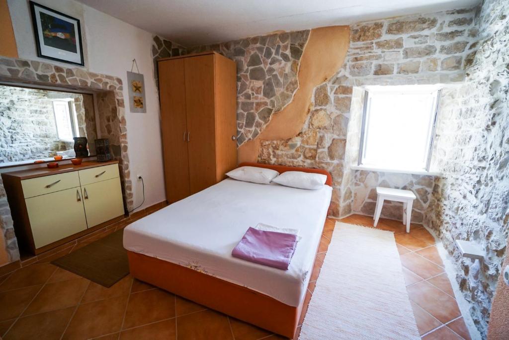sypialnia z łóżkiem i kamienną ścianą w obiekcie Lovely Apartment ES w mieście Umag
