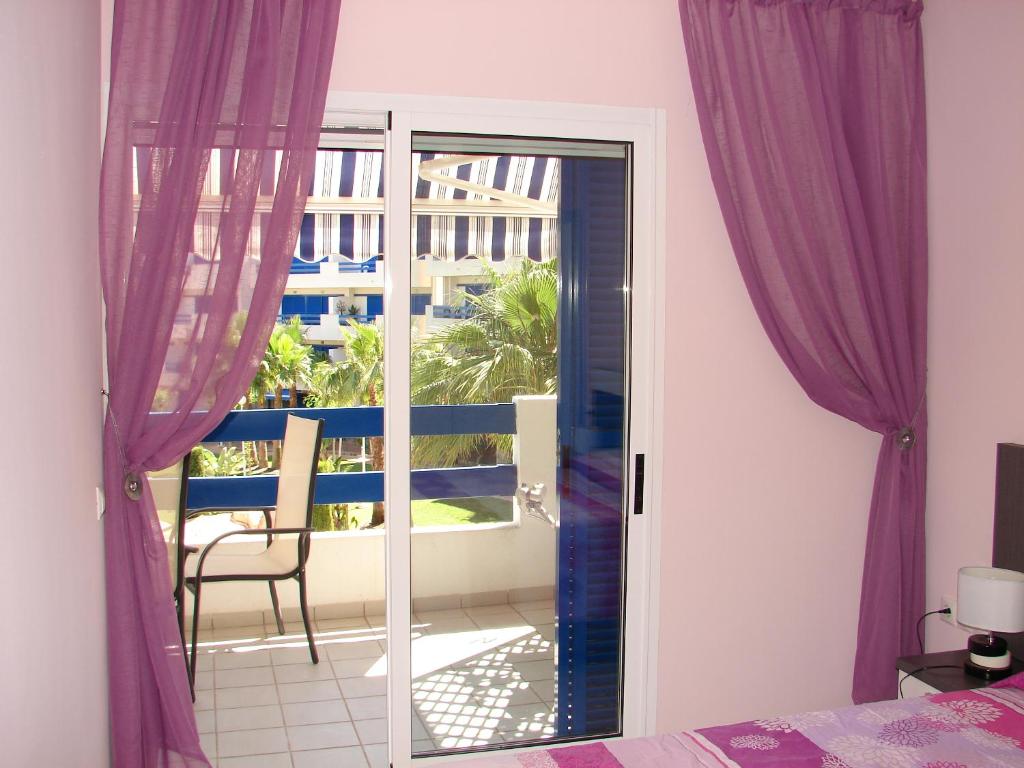 a bedroom with a door to a balcony with purple curtains at Apartamento en La Calma in Playas de Orihuela