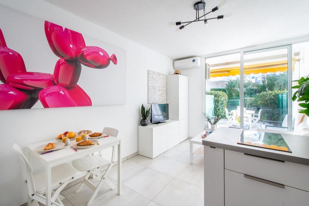 une cuisine avec des chaises roses et une table blanche dans l'établissement Sable et Mediterranée, à La Grande Motte